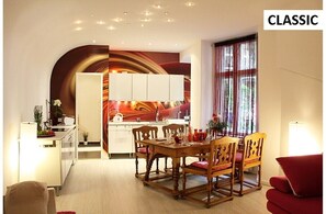 Ein kompakter Wohnraum mit Essbereich, Küche und einem roten Sofa.