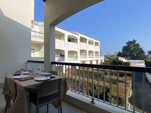 Un balcon avec une table dressée pour le dîner, donnant sur un immeuble doté de nombreux balcons et offrant une vue sur un ciel dégagé.