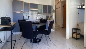 A modern kitchen with dark blue cabinets, a dining table with four chairs, and a small side table.