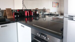 A modern kitchen with a black countertop, stainless steel appliances, and a white cabinetry.