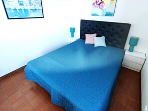 A bedroom with a large bed, a nightstand, a wall-mounted lamp, and a framed picture. - T3 in Cap d'Agde with pool, 30m to beach, sleeps 6 (Cap d'Agde)