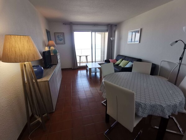A compact room with a bed, a desk, a chair, and a dining table.