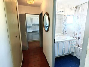 A narrow hallway leading to a bathroom with a sink, mirror, and shower curtain. - T3 in Cap d'Agde with pool, 30m to beach, sleeps 6 (Cap d'Agde)
