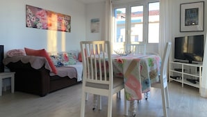 A cozy living room with a sofa, a dining table with chairs, a TV, and artwork on the walls. - Pleasant T3 with Air Conditioning and Wi-Fi, Balaruc-les-Bains (Balaruc-les-Bains)