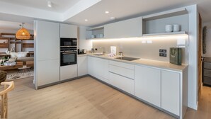 Une cuisine moderne avec des meubles blancs, un four encastré et un plan de travail doté d’un évier.