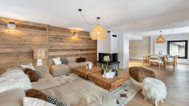 Un salon moderne doté d’une cheminée, de murs en bois et d’un coin repas baigné de lumière naturelle.
