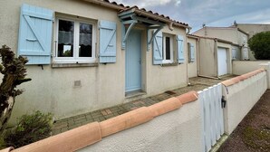 A row of houses with light blue shutters, a tiled roof, and a paved walkway. - Quiet house, 3 rooms, garden, WiFi - La Brée-les-Bains (La Brée-les-Bains)