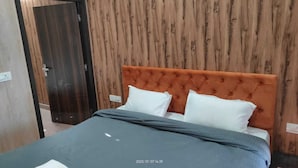 A bed with an orange headboard, white pillows, and a grey bedspread in a room with wooden panel walls. - 360 Degree View Homestay (Dehradun)