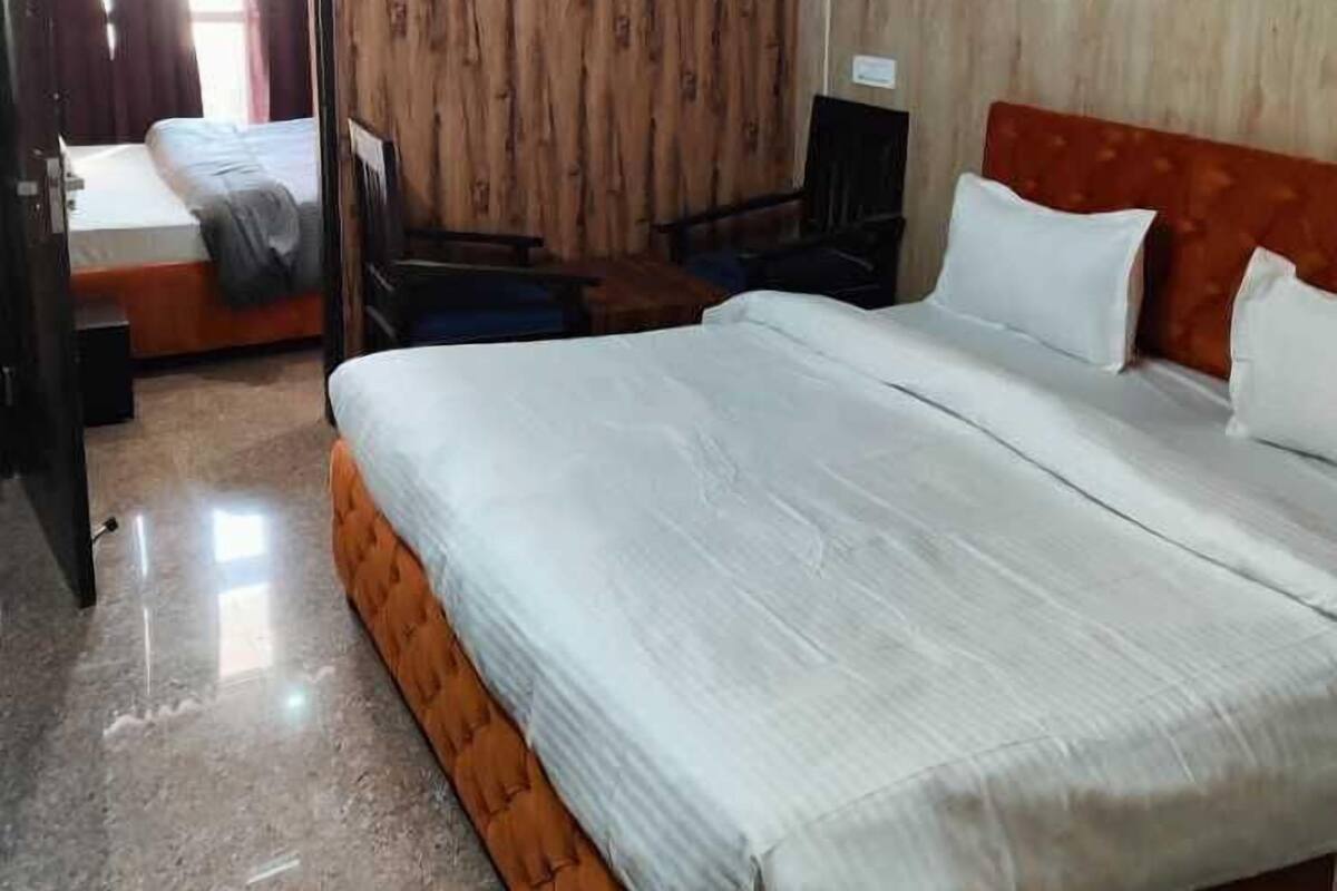 Un dormitori amb un llit gran, un ventilador de sostre, parets de fusta i una porta que dona a una altra habitació.