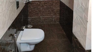 A bathroom with a toilet, a sink, and a water heater. - 360 Degree View Homestay (Dehradun)