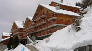 Ein mehrstöckiges Hotel mit Balkonen, gelegen an einem schneebedeckten Hang.