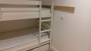Ein Etagenbett mit Holz-Kopfteil und weißer Wand.