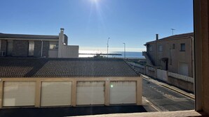 Une rue résidentielle offrant une vue dégagée sur la mer et baignée d’un soleil éclatant.