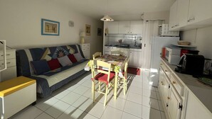 Un espace de vie compact comprenant un canapé, une table à manger et une kitchenette.
