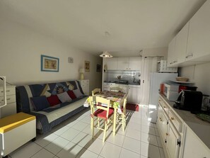 Espaço compacto para viver, com sofá, mesa de jantar e cozinha compacta.