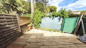 Une terrasse en bois, avec une clôture en bois et une bâche verte sur le côté droit.