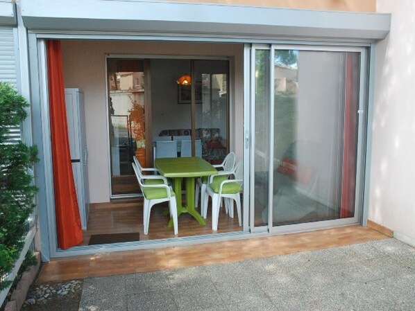 A patio with a table and chairs, a sliding glass door, and a view into the house.