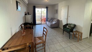 A compact living space with a dining area, a sofa, a small table, and a kitchenette. - Stylish 2BR Apt with Pool, AC & Terrace - Sleeps 6, 600m from Beach (Valras-Plage)