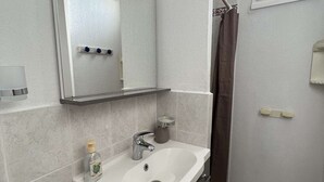 A bathroom with a white sink, a mirror, a towel rack, and a shower curtain. - Stylish 2BR Apt with Pool, AC & Terrace - Sleeps 6, 600m from Beach (Valras-Plage)
