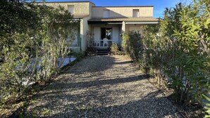 A two-story house with a gravel driveway leading to a covered porch. - Cozy 3-Room Pavilion with Pool, Near Beach and Shops, Sleeps 6 (Valras-Plage)