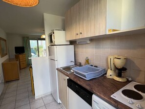 A compact kitchen with white appliances, a dishwasher, a sink, and a stove.