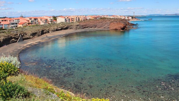 A coastal area with clear blue waters, a sandy beach, and buildings with red roofs. - Charming A/C T2 with pool and parking, 20m from the sea, sleeps 5 (Cap d'Agde)