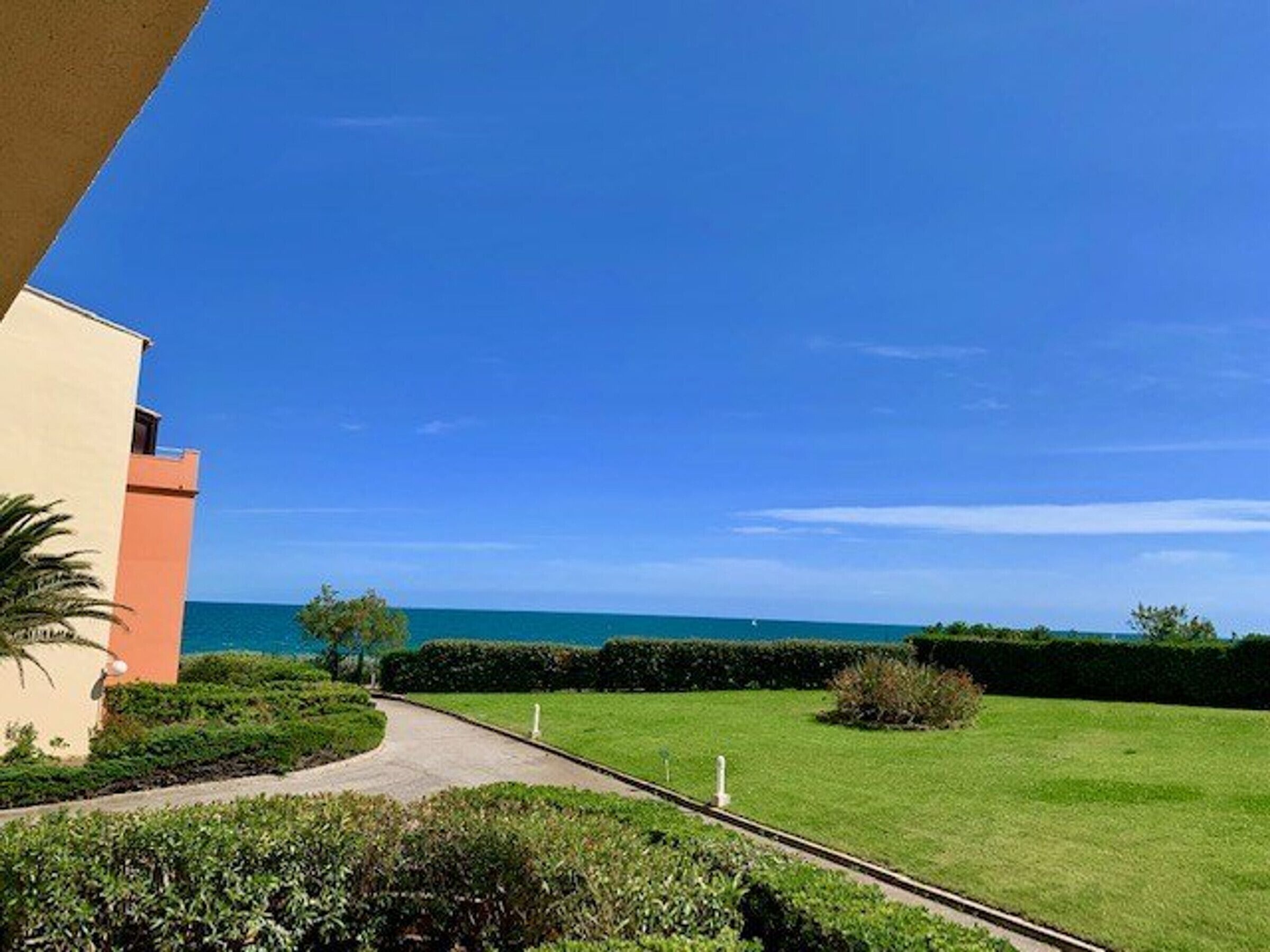 A pathway leading to a building with a view of the sea.