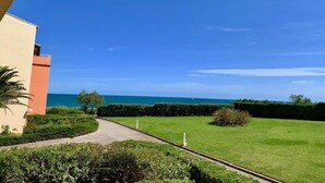A pathway leading to a building with a view of the sea. - Charming A/C T2 with pool and parking, 20m from the sea, sleeps 5 (Cap d'Agde)