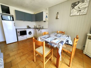 Cozinha compacta com área de jantar, incluindo mesa e cadeiras, máquina de lavar e micro-ondas.