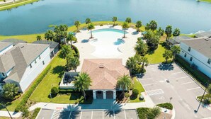 An aerial view of a hotel with a swimming pool, palm trees, and a parking lot. - Stunning 6BR Home • Pool, Spa, BBQ • Near Disney! (Kissimmee)