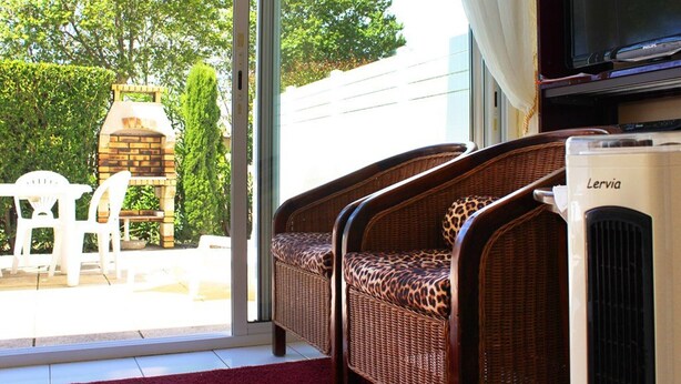 A room with wicker furniture, a television, and a Lervia air conditioning unit.