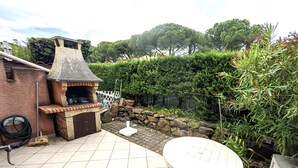 Un patio con horno de ladrillo, una mesa y un muro de piedra.