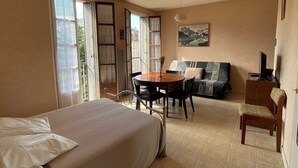 A bedroom with a bed, a dining table, a sofa, and a TV. - Spacious city-center studio, pets allowed (Aix-les-Bains)