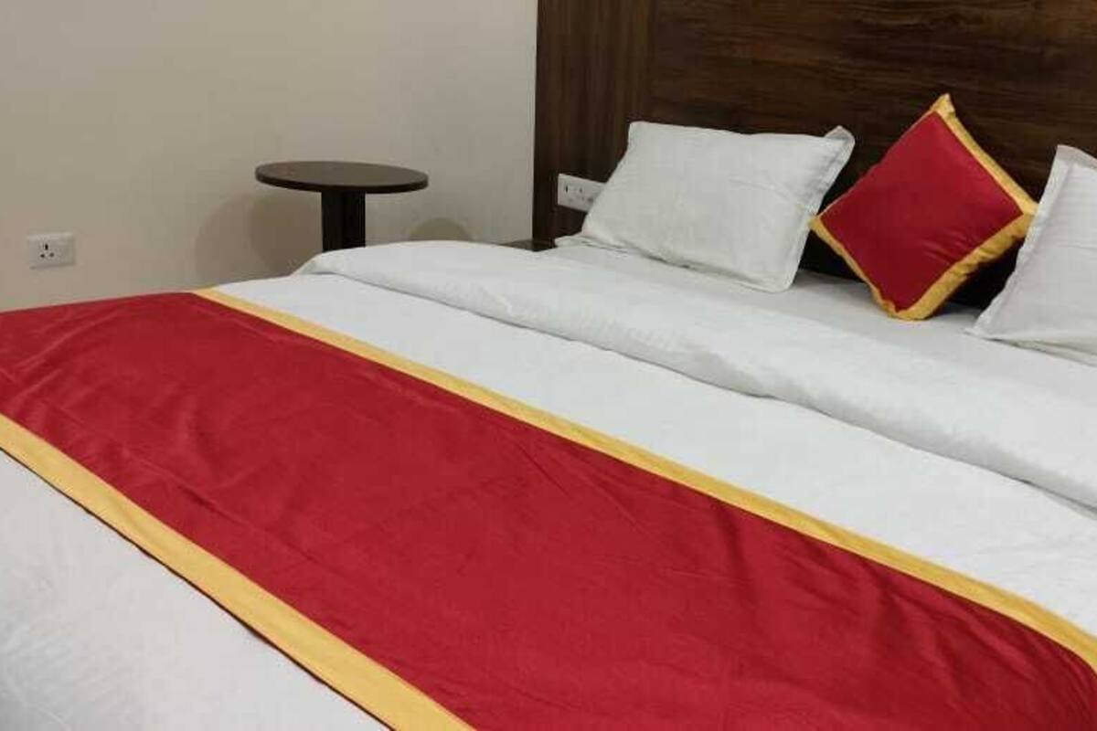 Un lit avec une literie blanche et une couvre-lit rouge et jaune.