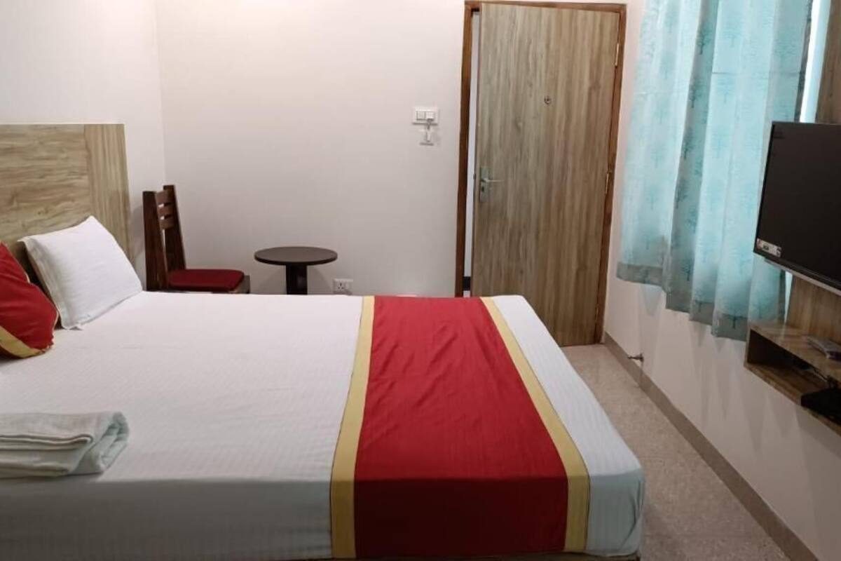 Une chambre d’hôtel avec un lit, une télévision, une armoire en bois, une petite table et une chaise.