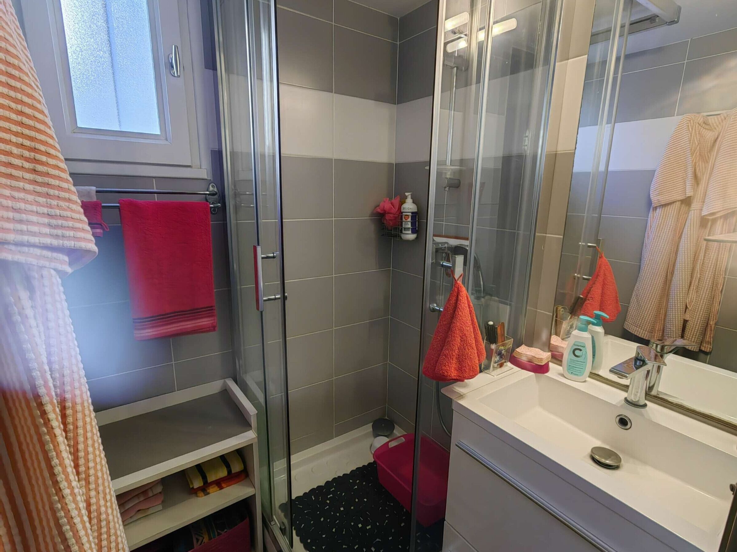 Une salle de bain moderne avec une douche à parois de verre, un lavabo blanc et un miroir.