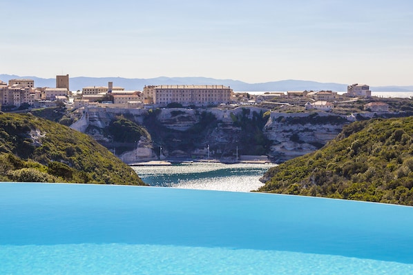 A coastal town with a prominent building overlooking a clear blue sea. - Résidence Terra Marina (Bonifacio)