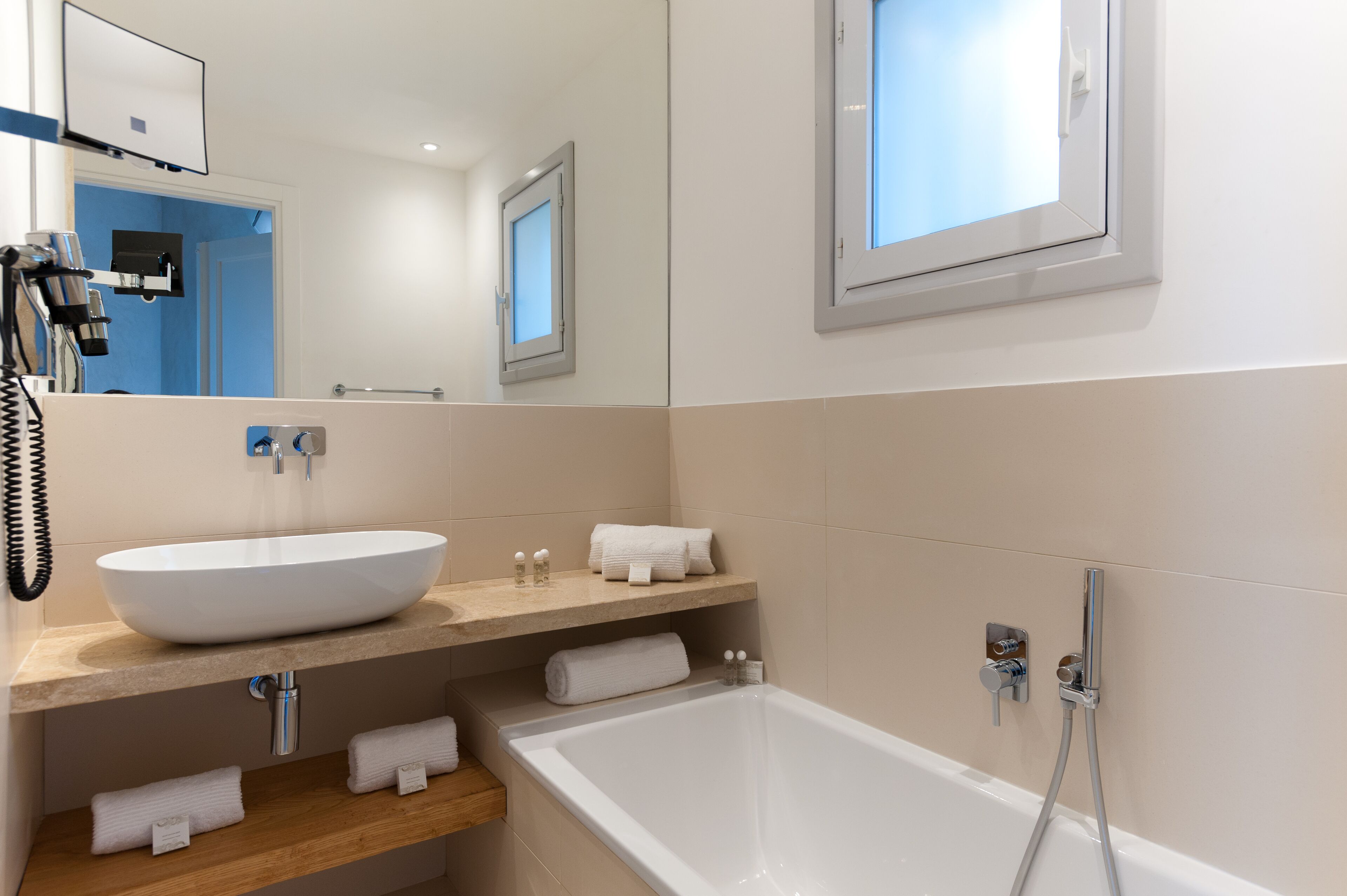 A modern bathroom with a large white bathtub, a vessel sink, and a mirror above the sink.