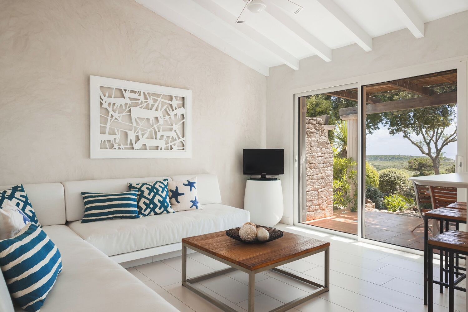 Una sala de estar moderna con un sofá, una mesa de centro, un televisor de pantalla plana y un ventanal que ofrece vistas al exterior.