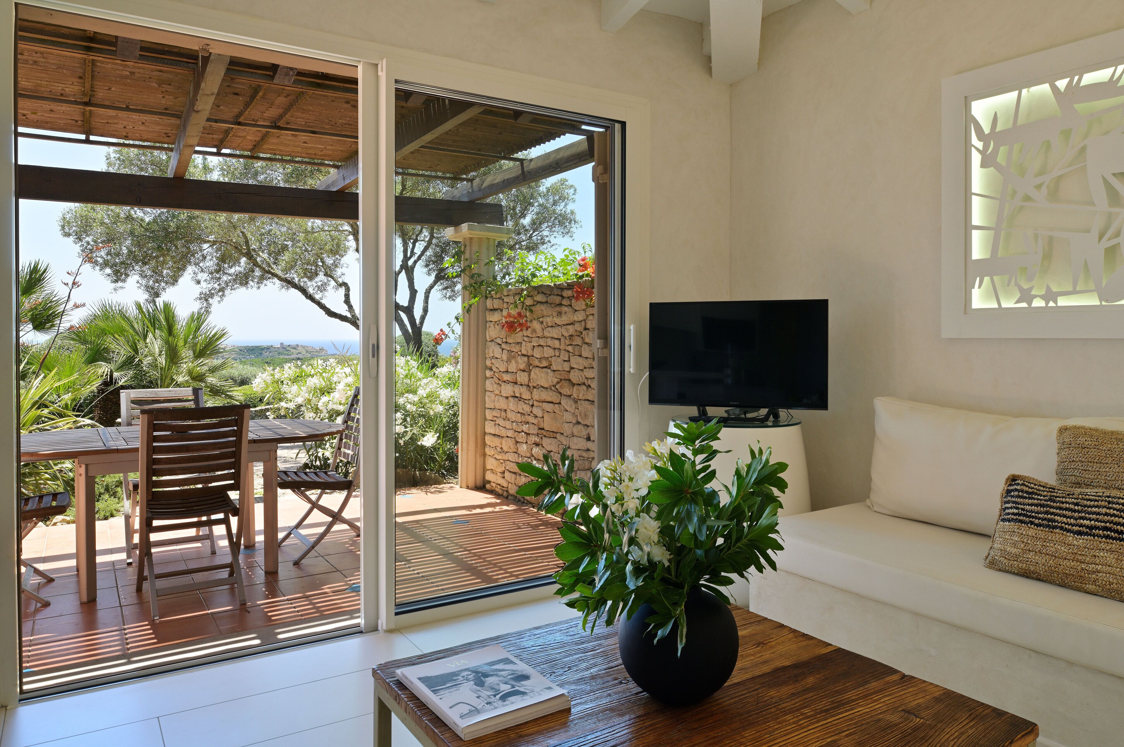 Una sala de estar moderna con televisor, sofá, mesa de centro y un comedor con mesa y sillas.