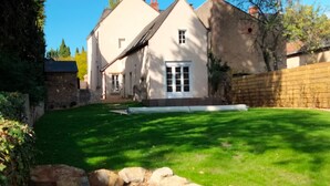 A house with a well-maintained lawn, a stone wall, and a large window.