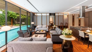 Een modern interieur met uitzicht op een zwembad, grijze banken en een eethoek.