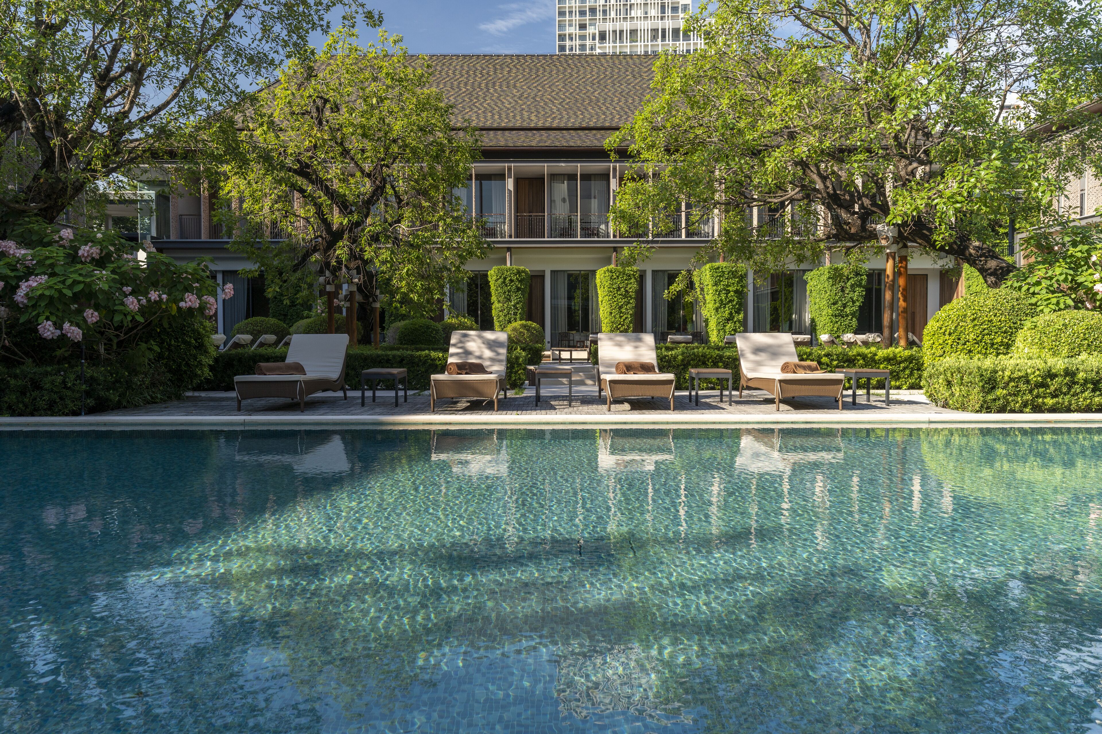 A pool area with lounge chairs and a building in the background.