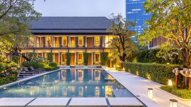 Een hotel met een zwembad, terras en een verzorgde tuin.