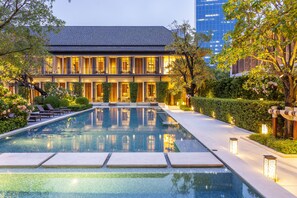 Un hotel con piscina, mobiliario exterior y un jardín bien cuidado.