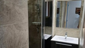 A modern bathroom with a glass-enclosed shower, a white sink, and dark cabinetry.