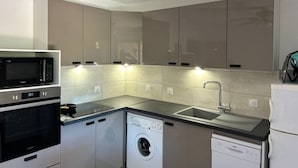 A compact kitchen with built-in appliances including a microwave, oven, dishwasher, and washing machine.
