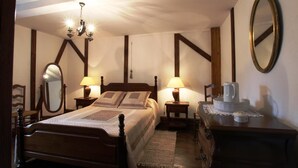 A bedroom with a wooden bed, two bedside tables with lamps, a dresser, a mirror, and a chandelier. - Country house in the heart of the bearn180 m2 (Sault-de-Navailles)