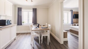 Una cocina moderna con armarios blancos, una mesa de comedor con sillas, un microondas y una computadora portátil.