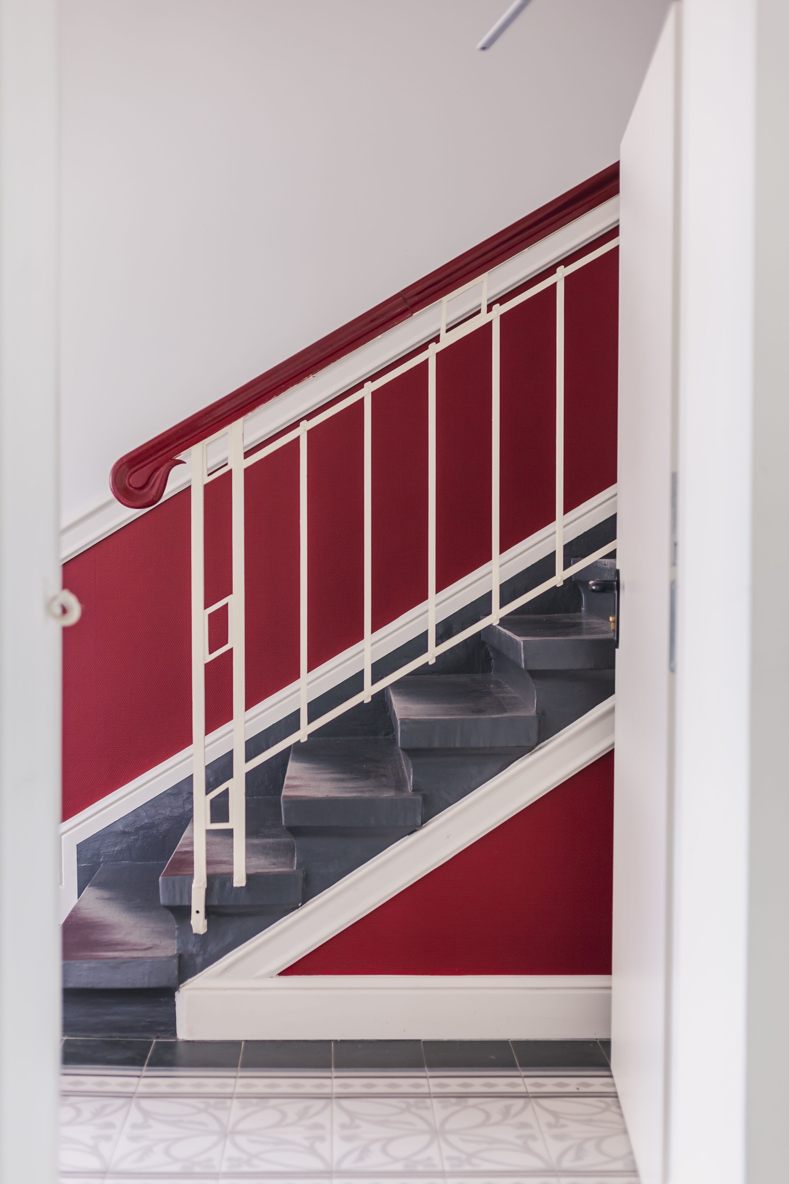 A staircase with a red wall and white handrail.